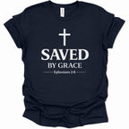A navy blue short-sleeve t-shirt with a white graphic print on the front featuring a cross, the text 'SAVED BY GRACE', and 'Ephesians 2:8'.
