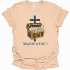 A light natural-colored short-sleeve t-shirt with a graphic of an open treasure chest filled with cash, a dark blue cross, and the text 'TREASURE & TRUTH' printed below.