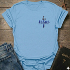 Light blue t-shirt with 'Jesus Alpha & Omega' and a Sword Christian T-Shirt Revelation 22:13 bold faith apparel Faith Forward design on a wooden surface with jeans and a Bible.