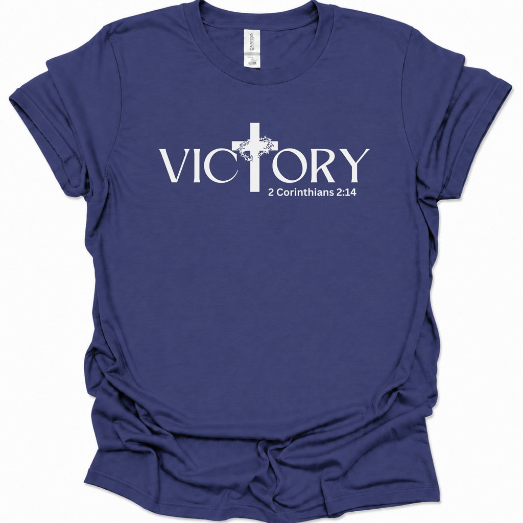 A purple blue short-sleeve t-shirt with a white graphic print on the front reading 'VICTORY' with a Christian cross replacing the letter 'I' and '2 Corinthians 2:14' beneath a cross design.