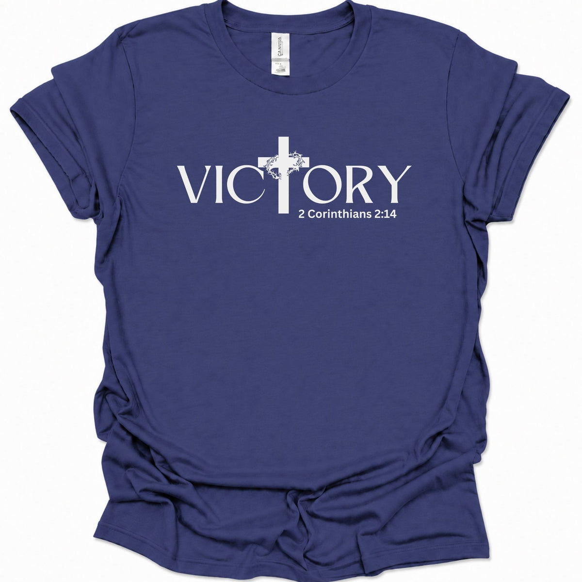 A purple blue short-sleeve t-shirt with a white graphic print on the front reading 'VICTORY' with a Christian cross replacing the letter 'I' and '2 Corinthians 2:14' beneath a cross design.