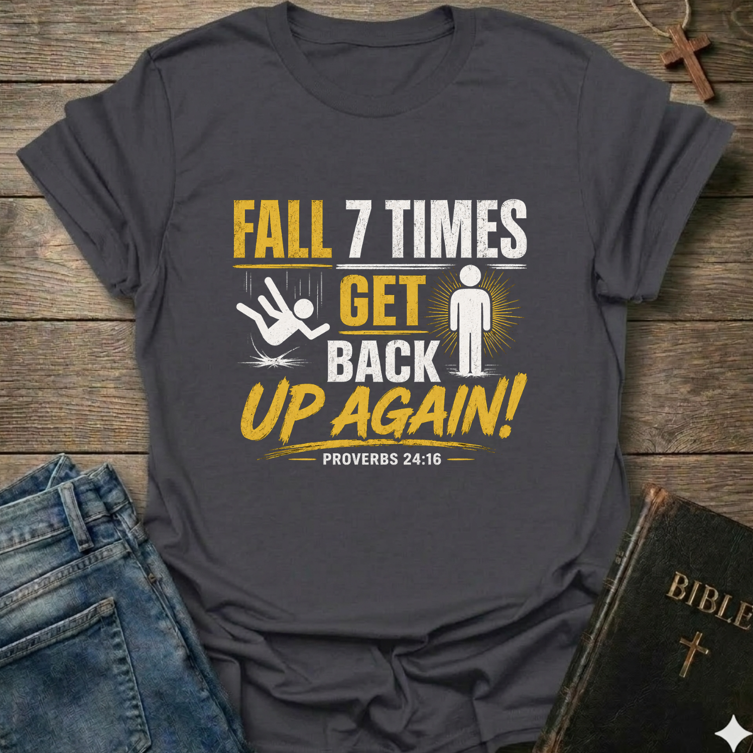 Gray t-shirt with motivational quote "Fall 7 Times Get Back Up Again Proverbs 24:16" bold graphic faith apparel Faith Forward on a wooden surface with jeans and a Bible.