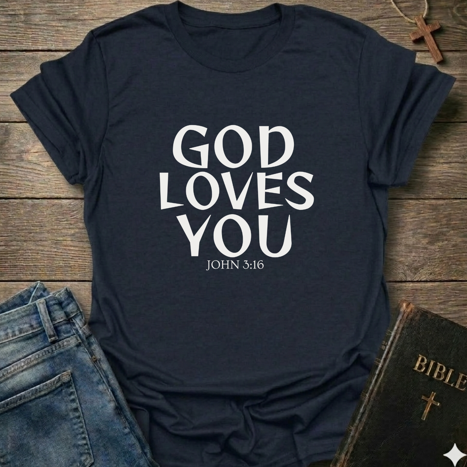 Navy blue t-shirt with 'GOD LOVES YOU' John 3:16 text Christian bold faith apparel Faith Forward on a wooden surface with jeans and a Bible.