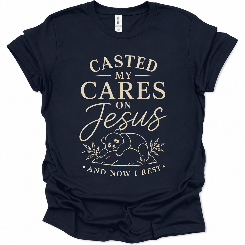 A navy blue short-sleeve t-shirt with a cream-colored graphic print on the front. The text reads 'CASTED MY CARES ON Jesus AND NOW I REST' with a small illustration of a panda bear and leaves below.