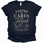 A navy blue short-sleeve t-shirt with a cream-colored graphic print on the front. The text reads 'CASTED MY CARES ON Jesus AND NOW I REST' with a small illustration of a panda bear and leaves below.