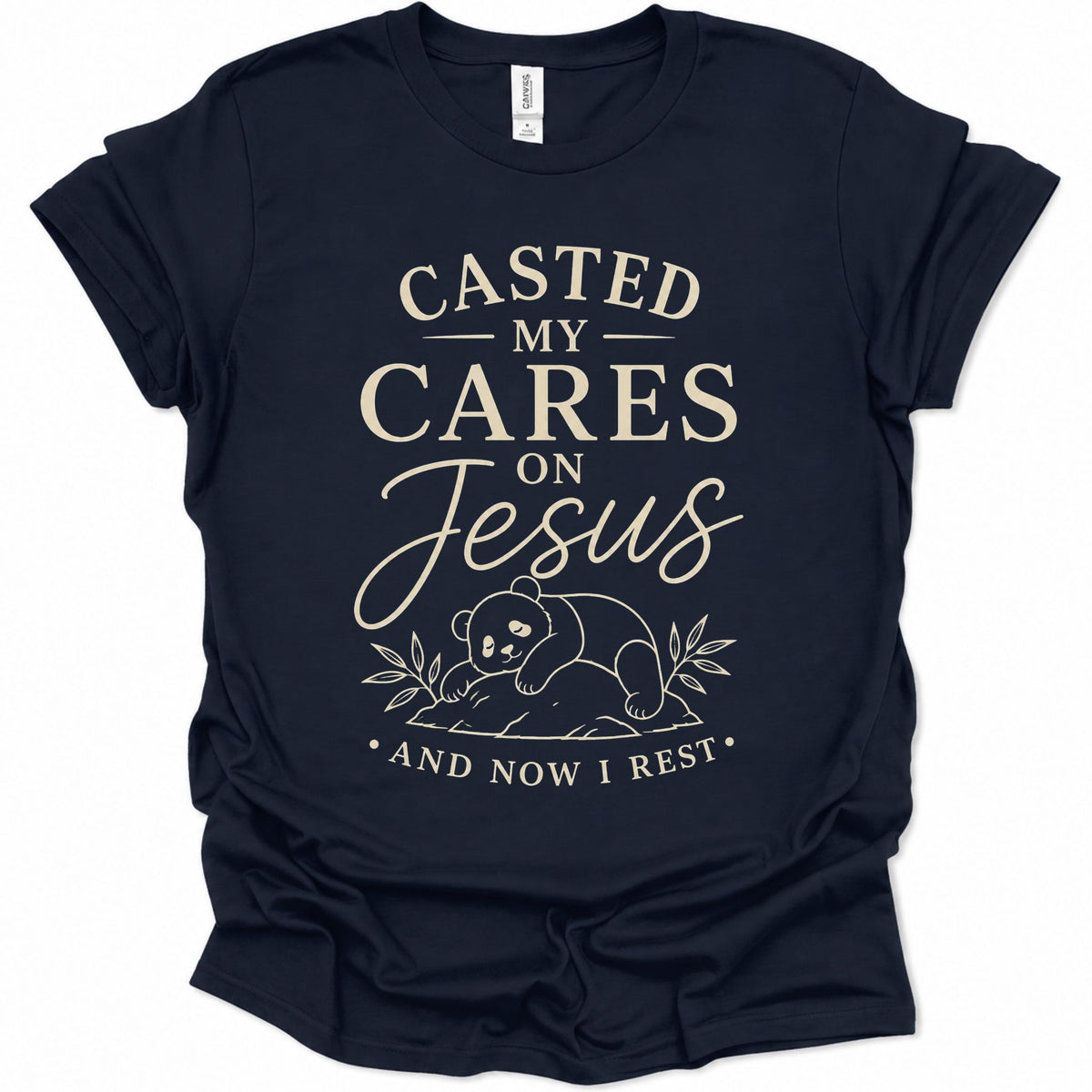 A navy blue short-sleeve t-shirt with a cream-colored graphic print on the front. The text reads 'CASTED MY CARES ON Jesus AND NOW I REST' with a small illustration of a panda bear and leaves below.