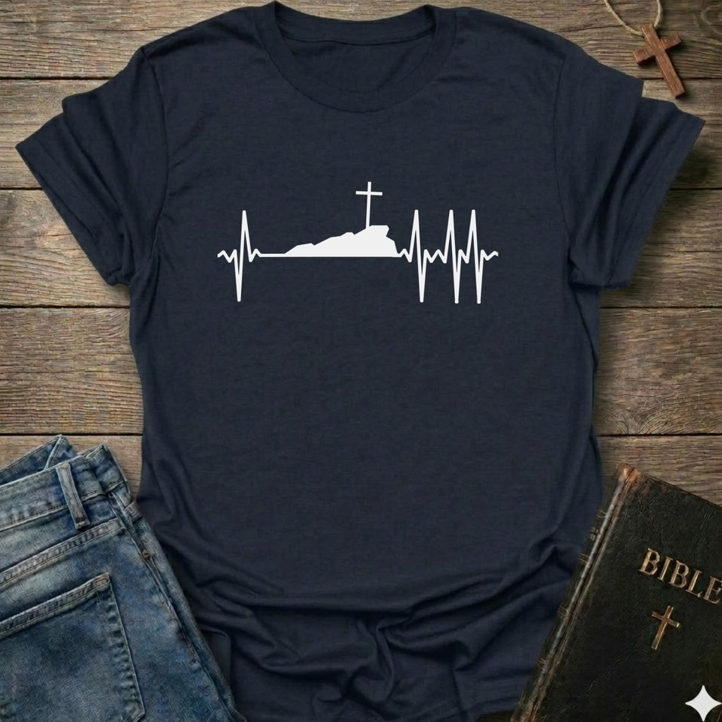 Navy blue T-shirt with a white graphic design Cross Heartbeat Lifeline Christian minimal faith apparel conversation starter on a wooden surface with jeans and a Bible.