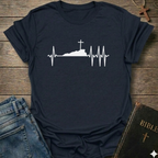 Navy blue T-shirt with a white graphic design Cross Heartbeat Lifeline Christian minimal faith apparel conversation starter on a wooden surface with jeans and a Bible.