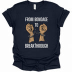 A navy blue short-sleeve graphic t-shirt laid flat on a white background. The shirt features a graphic of two raised fists connected by broken handcuffs, with the text 'FROM BONDAGE TO BREAKTHROUGH' printed in white above and below the illustration.