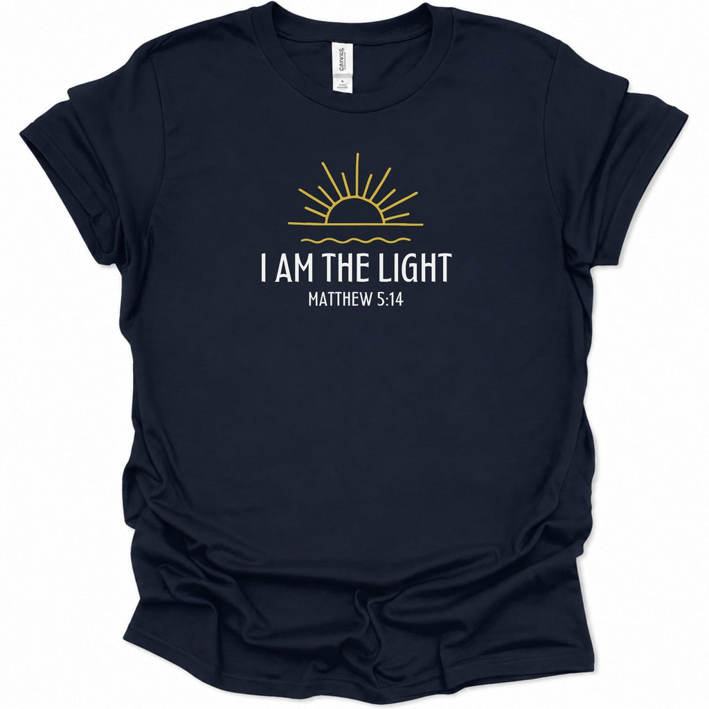 A navy blue short-sleeve t-shirt with a graphic on the chest featuring a yellow sun and the text 'I AM THE LIGHT MATTHEW 5:14' in white, displayed on a clean white background.