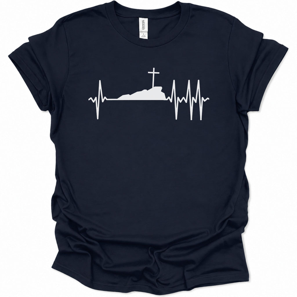 A navy blue short-sleeve t-shirt with a white graphic print of a heartbeat EKG line forming a silhouette of a hill with a cross on top, displayed on a clean white background.