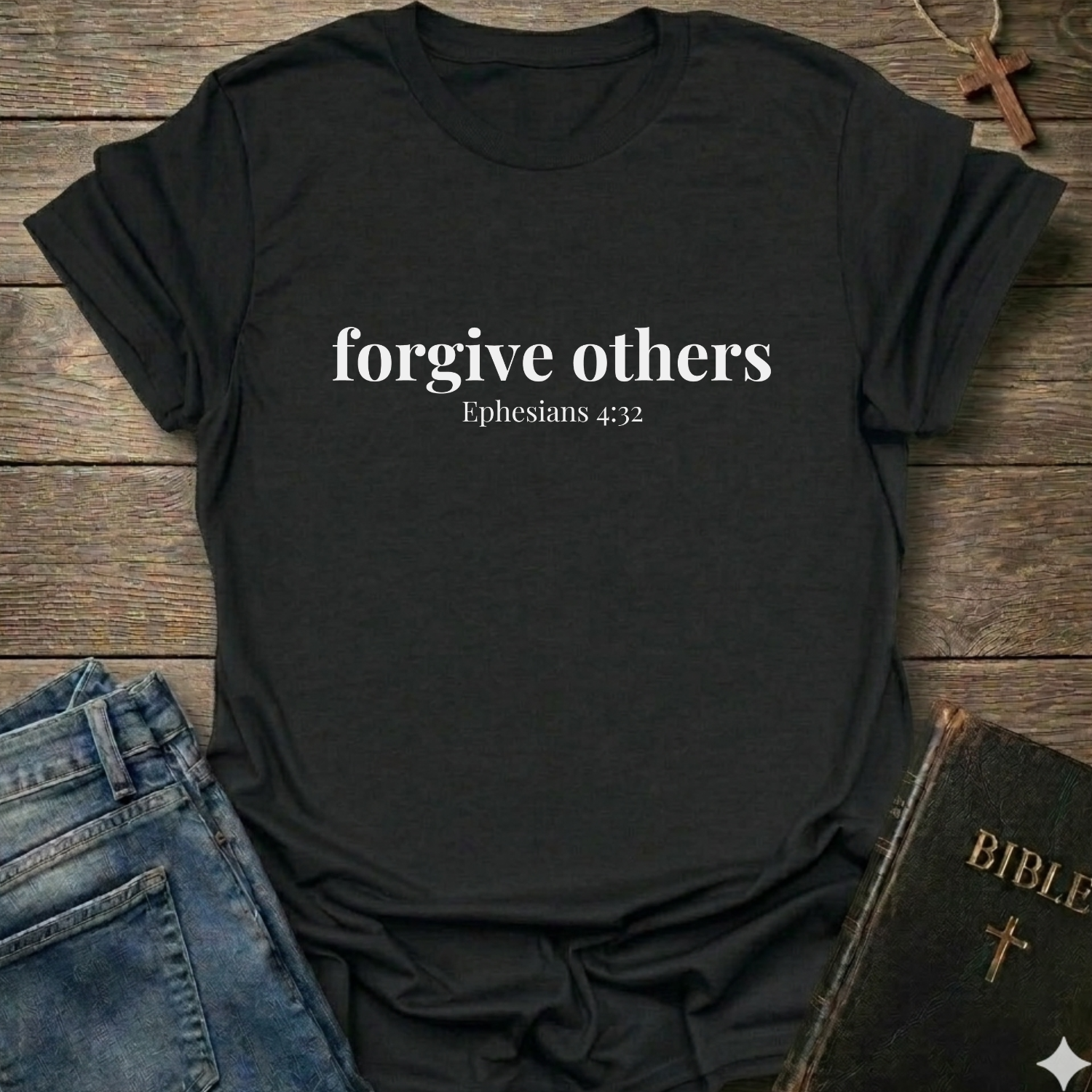 Black t-shirt with 'forgive others Ephesians 4:32' text on a wooden surface with jeans and a Bible.