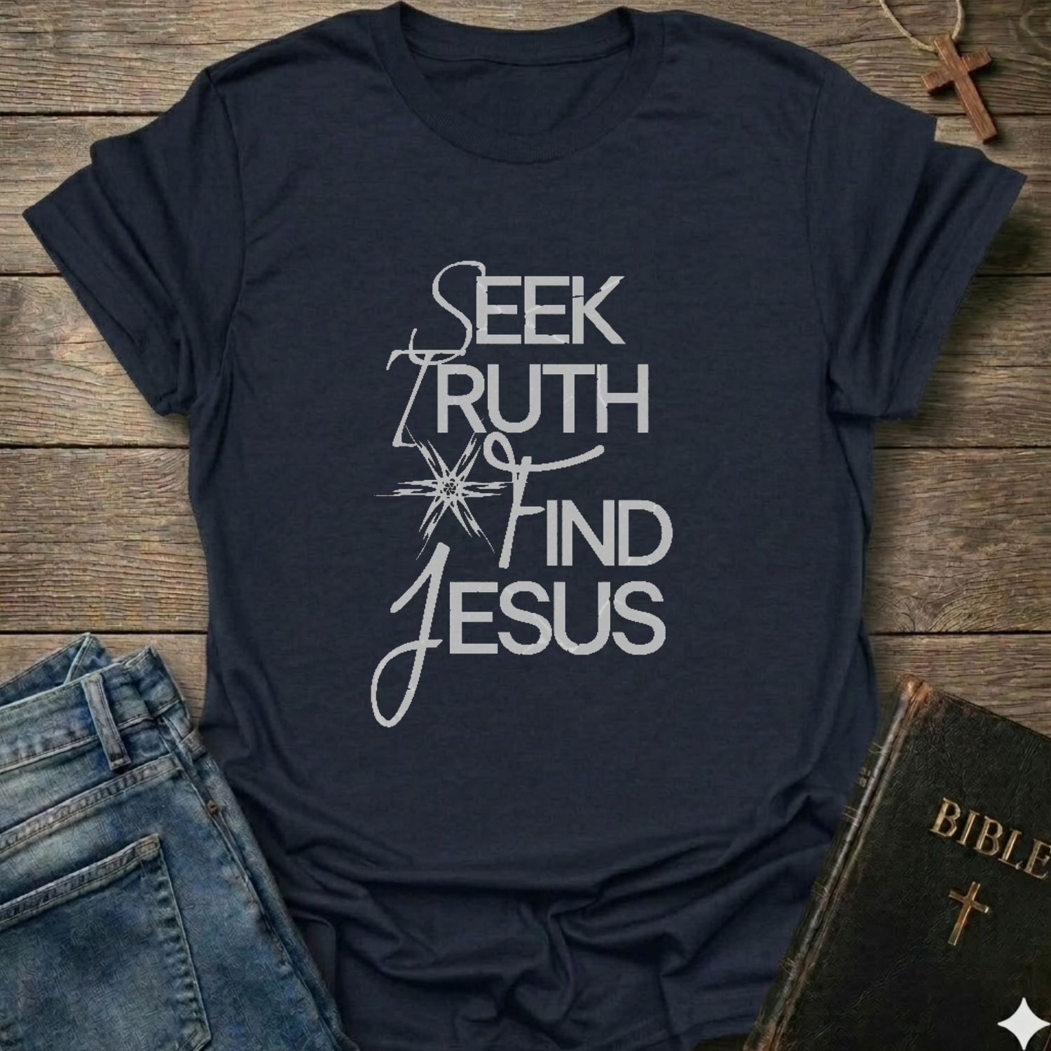 Navy blue t-shirt with 'Seek Truth Find Jesus' text on a wooden surface with jeans and a Bible. Bold typography faith apparel conversation starter.