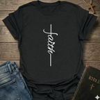 Black t-shirt with 'faith' design on a wooden surface with jeans and a Bible. Faith Minimalist Cross Script Christian T-Shirt bold faith apparel Faith Forward