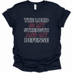 A navy blue short-sleeve t-shirt with a graphic text print reading 'THE LORD IS MY STRENGTH AND MY DEFENSE' in white and red lettering, displayed on a clean white background.