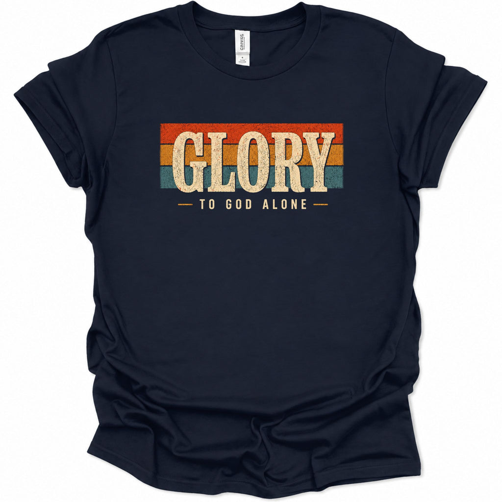 A navy blue short-sleeve t-shirt with a retro-style graphic on the chest that reads 'GLORY TO GOD ALONE' in distressed beige lettering over horizontal orange, red, and teal stripes, shown on a plain white background.