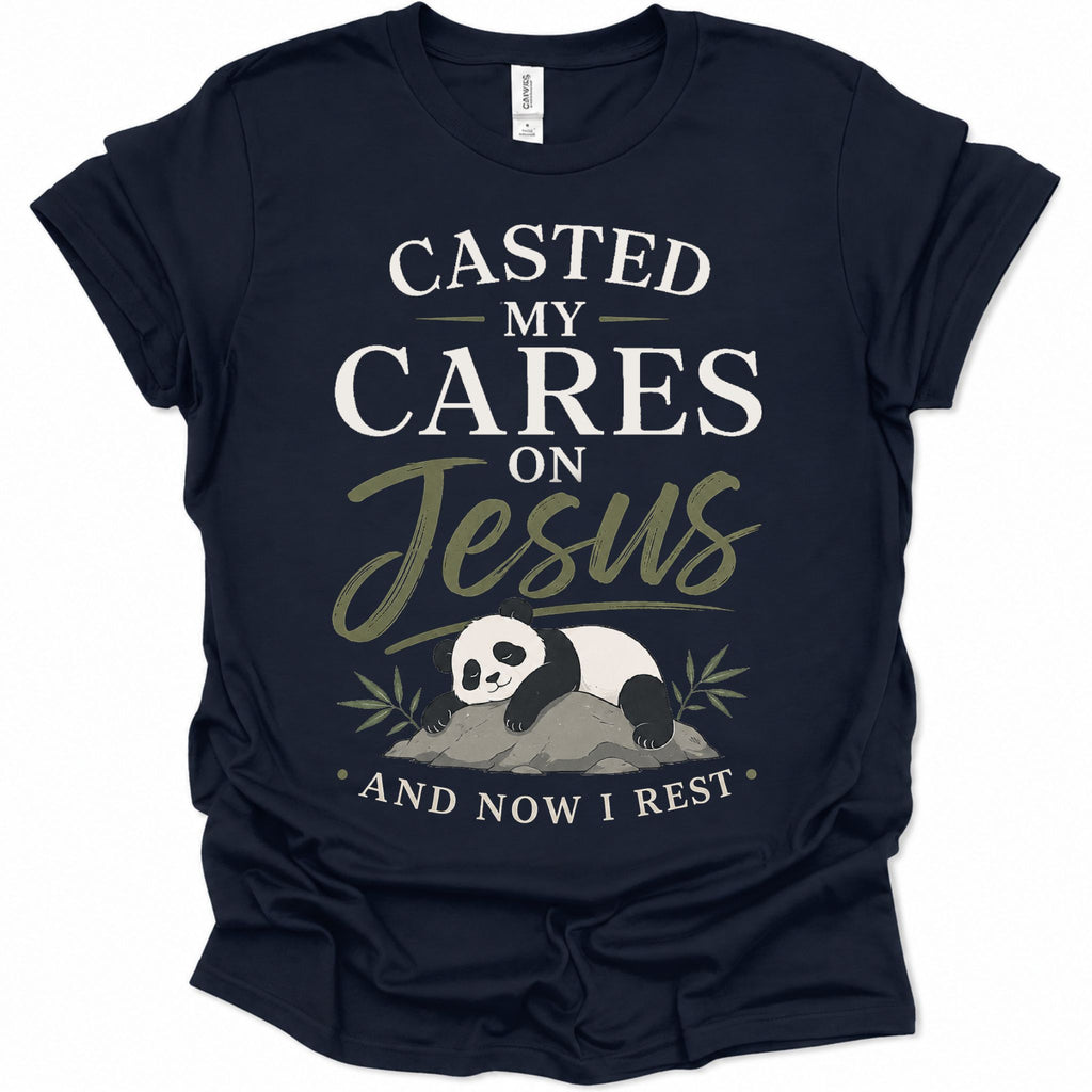 A navy blue short-sleeve t-shirt with a graphic print on the front. The print features the text 'CASTED MY CARES ON Jesus AND NOW I REST' in white and olive green lettering, along with an illustration of a sleeping panda resting on a rock with bamboo leaves.