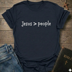 Navy tshirt  'Jesus > people' Christian faith apparel conversation starter text on a wooden surface with jeans and a Bible.