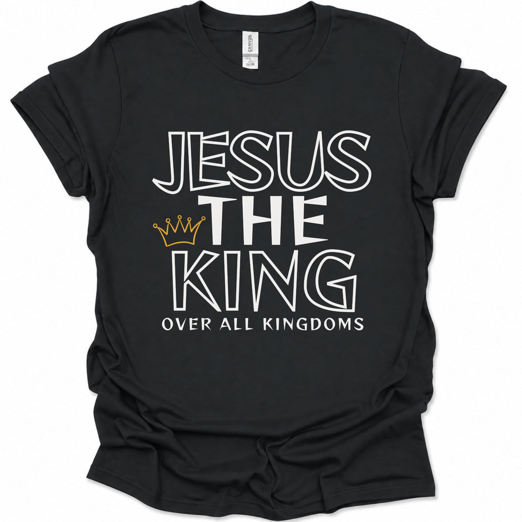 A black short-sleeve t-shirt with a graphic print reading 'JESUS THE KING OVER ALL KINGDOMS' in white outlined lettering, featuring a small gold crown icon between 'THE' and 'KING'.