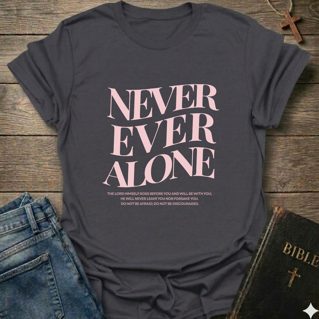 Gray t-shirt with 'NEVER EVER ALONE' text on a wooden surface with jeans and a Bible. Never Ever Alone Never Forsaken Christian T-Shirt Deuteronomy 31:8 bold faith apparel Faith Forward