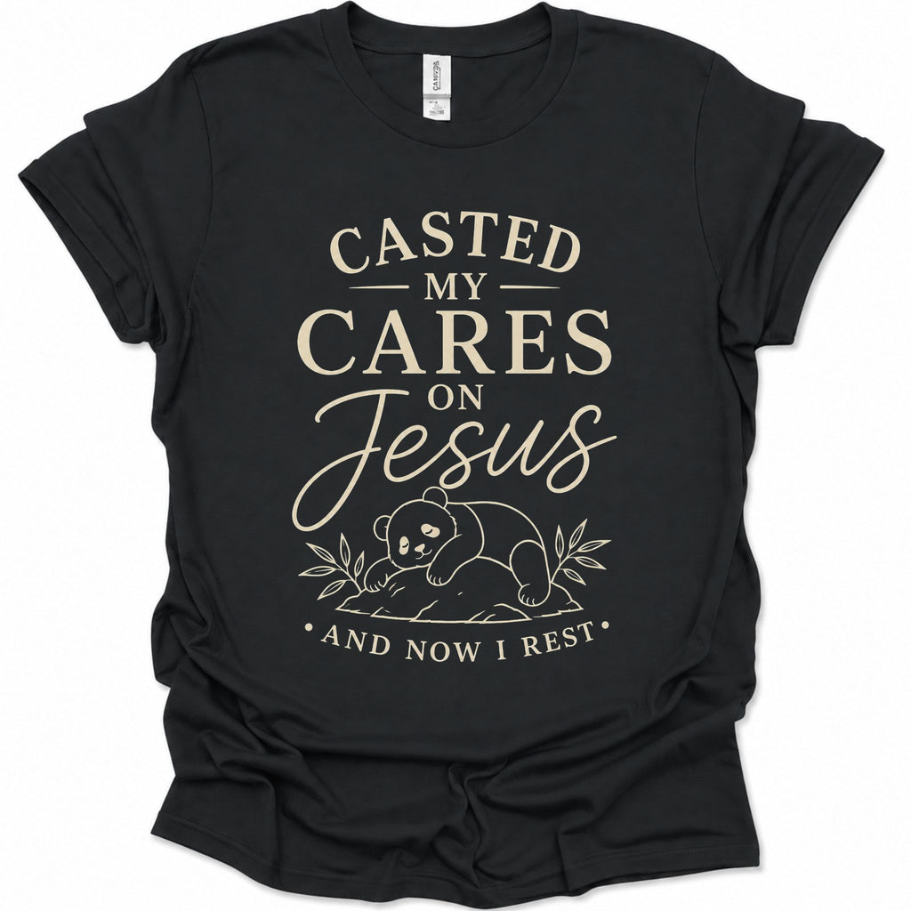 A black short-sleeve graphic t-shirt with a cream-colored text print reading 'CASTED MY CARES ON Jesus AND NOW I REST' and a small bear illustration, shown on a plain white background.