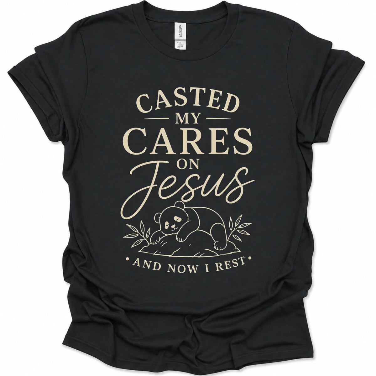 A black short-sleeve graphic t-shirt with a cream-colored text print reading 'CASTED MY CARES ON Jesus AND NOW I REST' and a small bear illustration, shown on a plain white background.