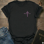 Black t-shirt with a purple cross and 'Redeemed' text on a wooden surface with jeans and a Bible.