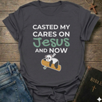 Gray t-shirt Casted My Cares on Jesus Christian relatable faith apparel conversation starter with a panda graphic and text on a wooden surface with jeans and a Bible.
