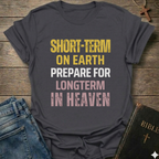 Gray t-shirt with text "Short Term on Earth Prepare for Long Term in Heaven" Christian T-Shirt bold faith apparel conversation starter, on a wooden surface with jeans and a Bible.
