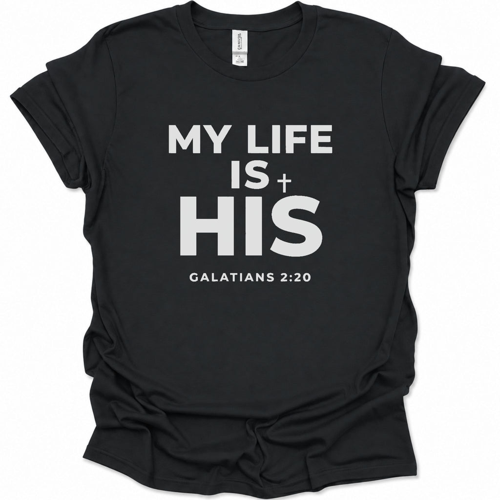 A black short-sleeve crewneck t-shirt with bold black text on the front reading 'MY LIFE IS + HIS' and 'GALATIANS 2:20' underneath, shown on a plain white background.