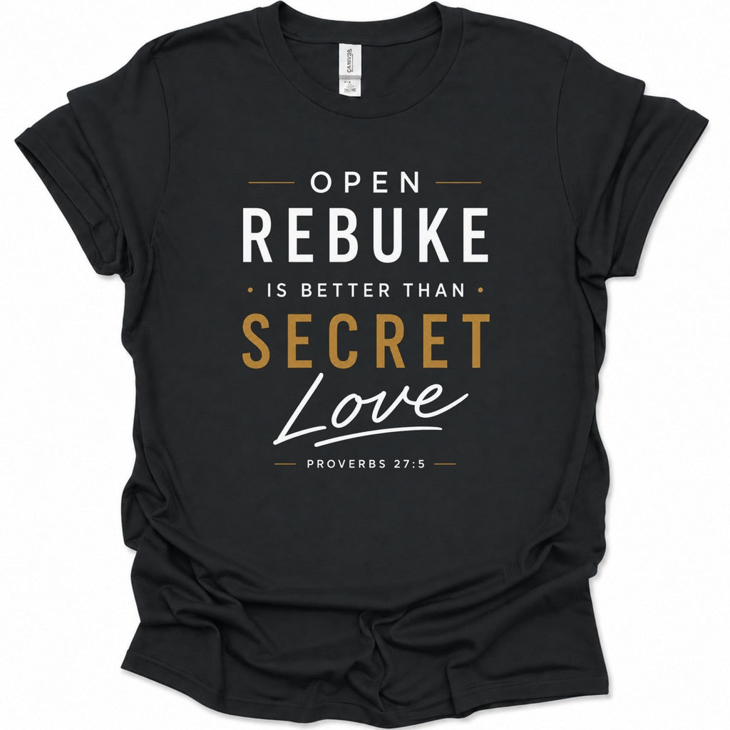 A black short-sleeve t-shirt with a graphic text print reading 'OPEN REBUKE IS BETTER THAN SECRET Love PROVERBS 27:5' in white and gold lettering, shown on a plain white background.