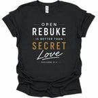A black short-sleeve t-shirt with a graphic text print reading 'OPEN REBUKE IS BETTER THAN SECRET Love PROVERBS 27:5' in white and gold lettering, shown on a plain white background.