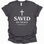 A dark heather gray short-sleeve t-shirt with a distressed white graphic print on the front featuring a cross, the words 'SAVED BY GRACE', and 'Ephesians 2:8'.