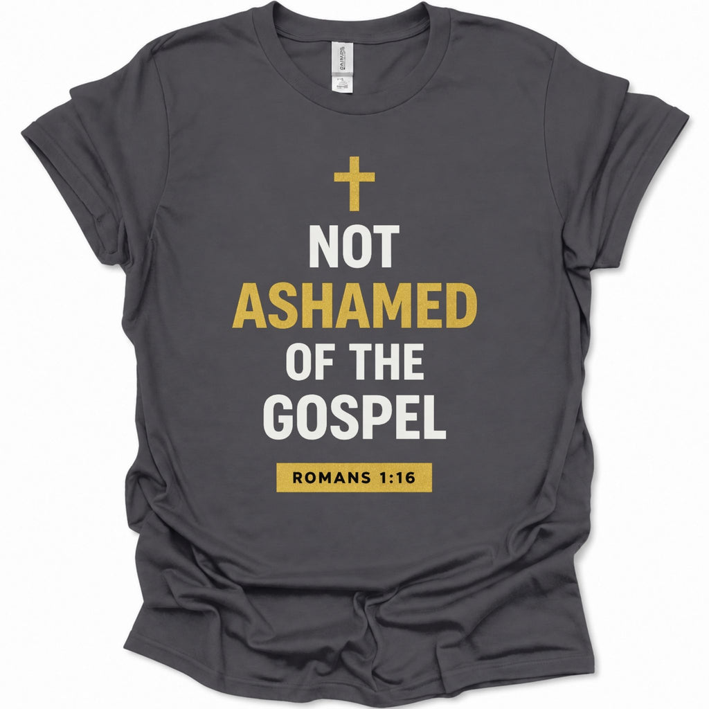 A dark heather gray short-sleeve t-shirt with a graphic print on the front. The print features a gold Christian cross, the text 'NOT ASHAMED OF THE GOSPEL' in white and gold, and a gold box containing 'ROMANS 1:16' at the bottom.