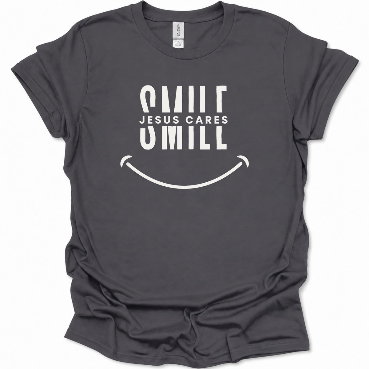 A dark heather gray short-sleeve t-shirt with a white graphic print that reads 'SMILE JESUS CARES SMILL' above a smiley face, shown on a plain white background.