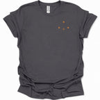 A dark heather gray short-sleeve t-shirt with a small orange graphic on the left chest consisting of three dots and a cross sign, displayed on a clean white background.