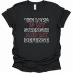 A black short-sleeve t-shirt with a graphic text print reading 'THE LORD IS MY STRENGTH AND MY DEFENSE' in white and red lettering, displayed on a clean white background.