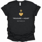 A black short-sleeve t-shirt with a gold and white graphic on the chest featuring a cross, a heart, the word 'TREASURE', an arrow, 'HEART', and 'MATTHEW 6:21'.