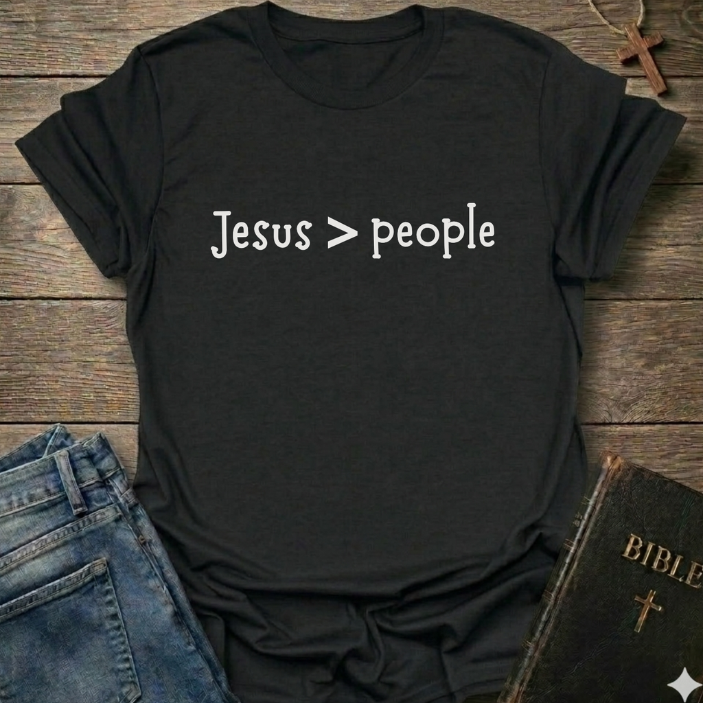 Black t-shirt  'Jesus > people' Christian faith apparel conversation starter text on a wooden surface with jeans and a Bible.