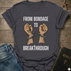 Gray t-shirt with text 'From Bondage to Breakthrough' Christian T-Shirt and broken chains graphic faith apparel conversation starter
on a wooden surface.