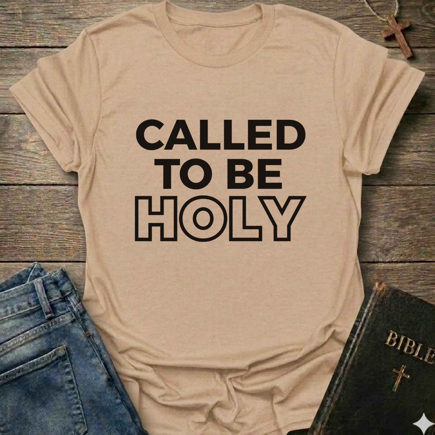 Natural t-shirt with 'Called to be Holy' Christian T-Shirt bold faith apparel 1 Peter 1:15 conversation starter text on a wooden surface with jeans and a Bible.