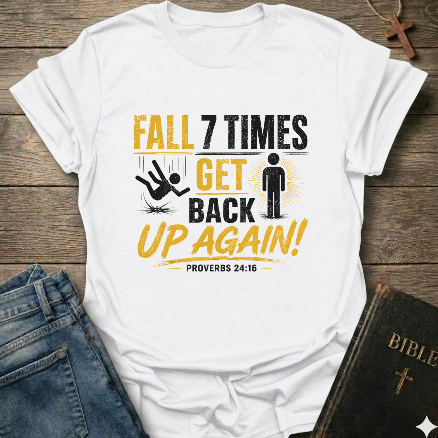 White t-shirt with motivational quote "Fall 7 Times Get Back Up Again Proverbs 24:16" bold graphic faith apparel Faith Forward on a wooden surface with jeans and a Bible.
