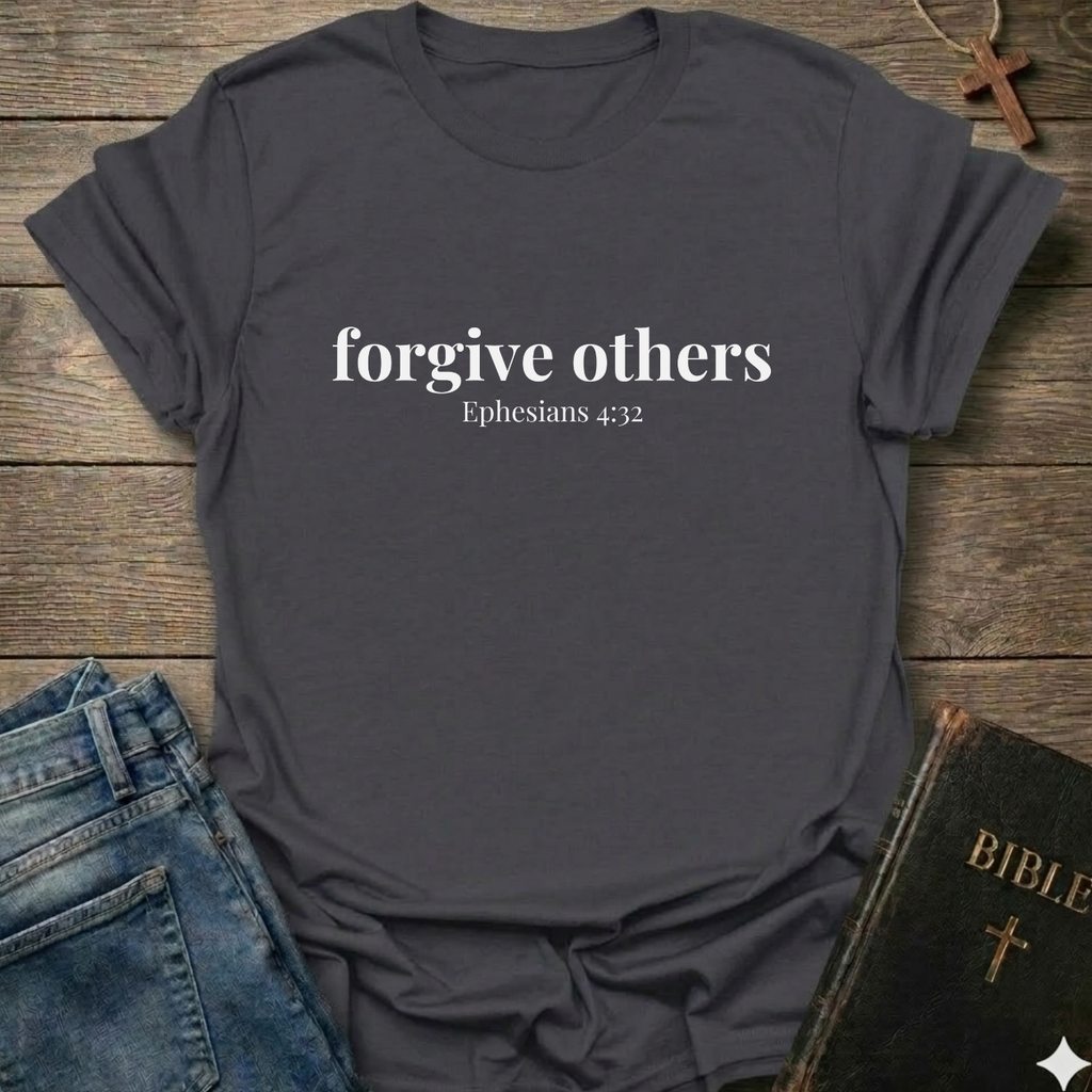 Gray t-shirt with 'forgive others Ephesians 4:32' text on a wooden surface with jeans and a Bible.