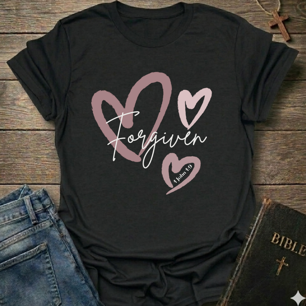 Black t-shirt with 'Forgiven' text and pink hearts on a wooden surface with jeans and a Bible. Forgiven Christian T-Shirt 1 John 1:9 bold faith apparel Faith Forward women