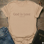 Natural t-shirt with 'God is Love'  Christian T-Shirt 1 John 4:15 elegant faith apparel Faith Forward text. T-shirt on a wooden surface with jeans and a Bible.