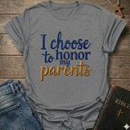 Gray t-shirt with 'I choose to honor my parents' Exodus 20:12 text navy gold Christian faith apparel conversation starter. T-shirt is on a wooden surface with jeans and a Bible.
