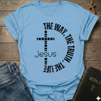 Light blue t-shirt with a cross and text  "Jesus The Way The Truth The Life Cross Circle John 14:6" Christian faith apparel Faith Forward. It is on a wooden surface with jeans and a Bible.