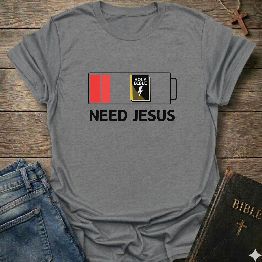 Gray t-shirt with 'Need Jesus' graphic on a wooden surface with jeans and a Bible. Need Jesus to Recharge My Battery Christian T-Shirt bold faith apparel Faith Forward