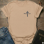 Natual t-shirt with a cross and 'Redeemed' text Christian minimal faith apparel Faith Forward on a wooden surface with jeans and a Bible.