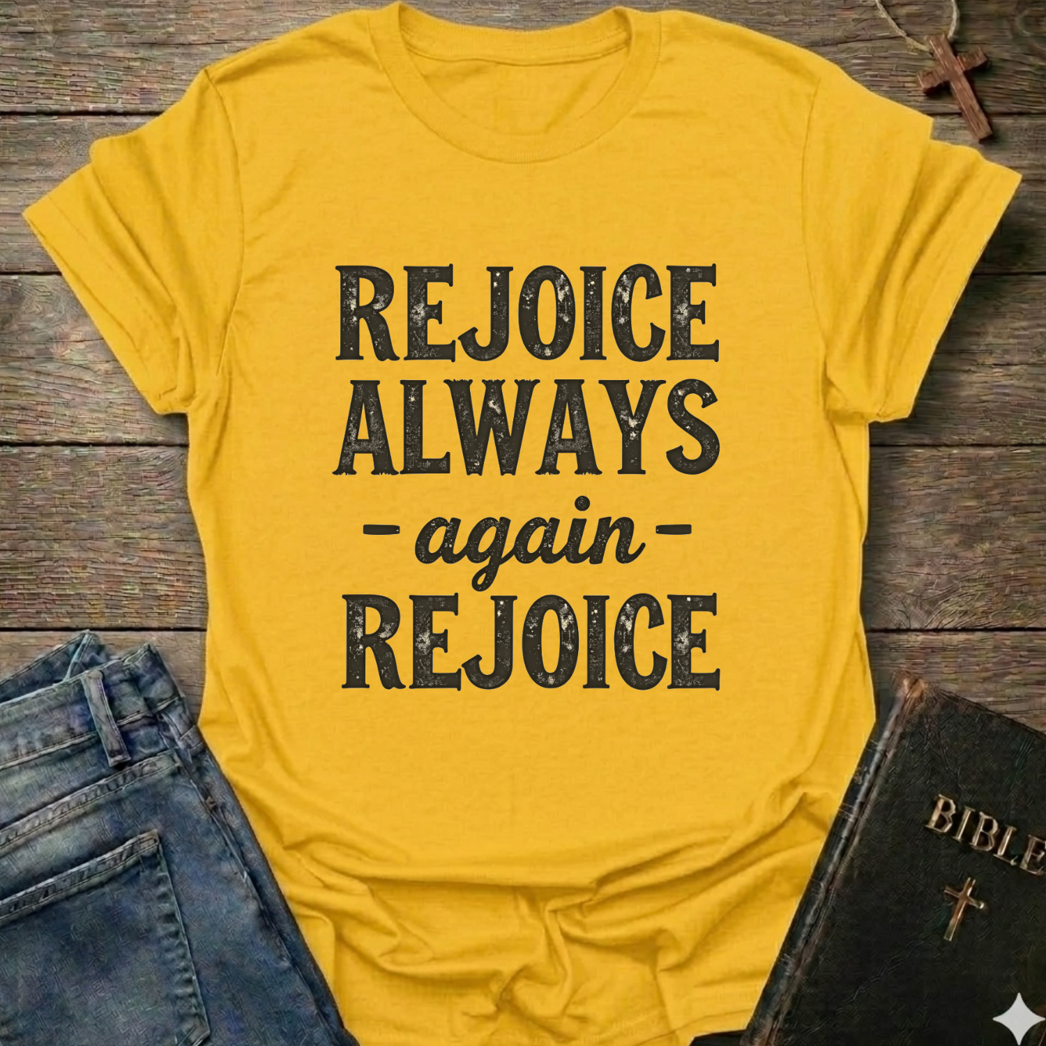 Yellow t-shirt with 'REJOICE ALWAYS again REJOICE' text Philippians 4:4 bold faith apparel Faith Forward on a wooden surface with jeans and a Bible.